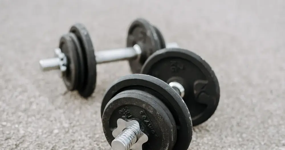 Halteres de ferro no asfalto, imagem de treino para quem busca sites para achar personal trainer em Brasília